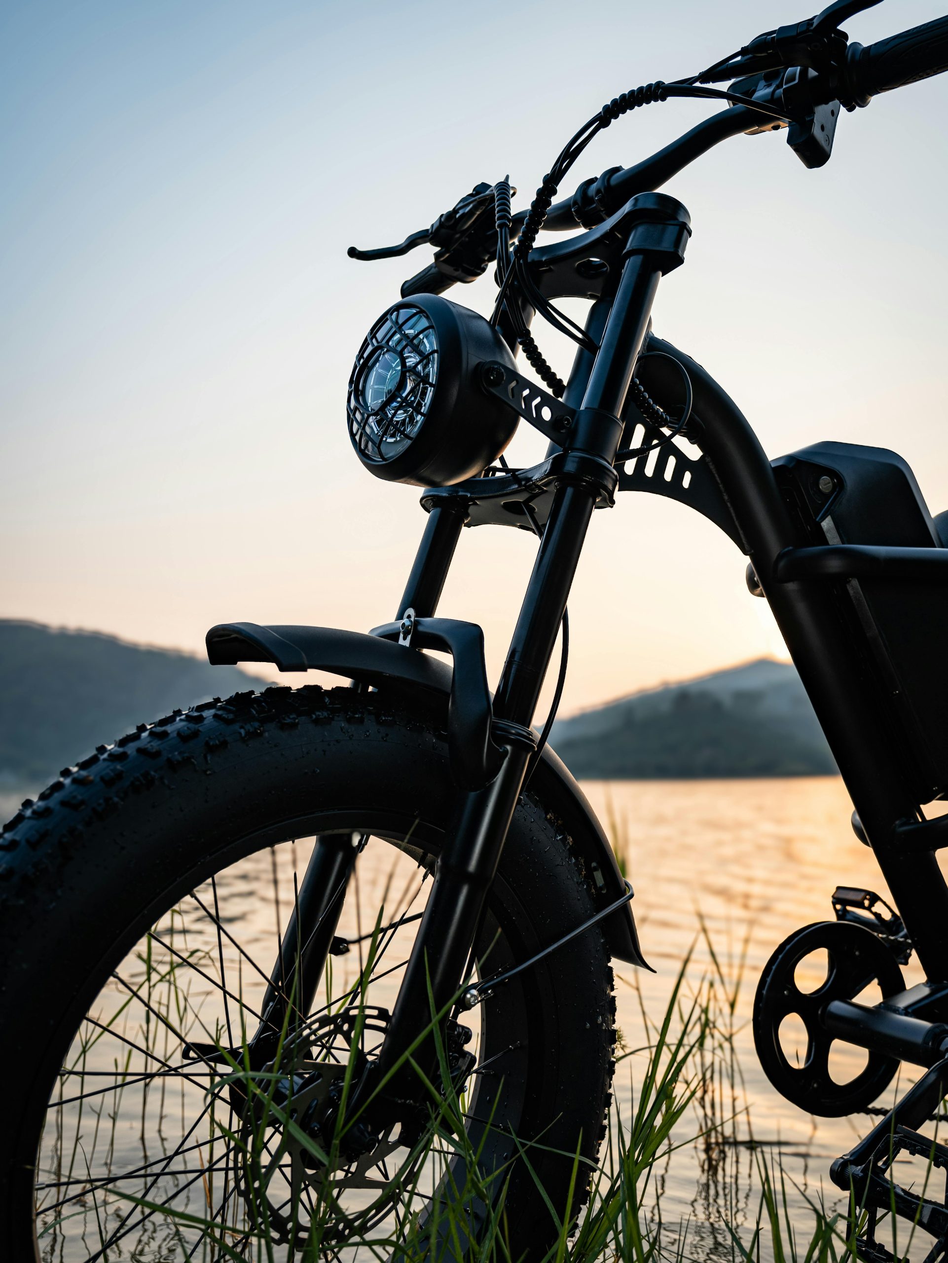 Close-up of an electric bike by a lake during sunset, highlighting its modern design and adventurous spirit.